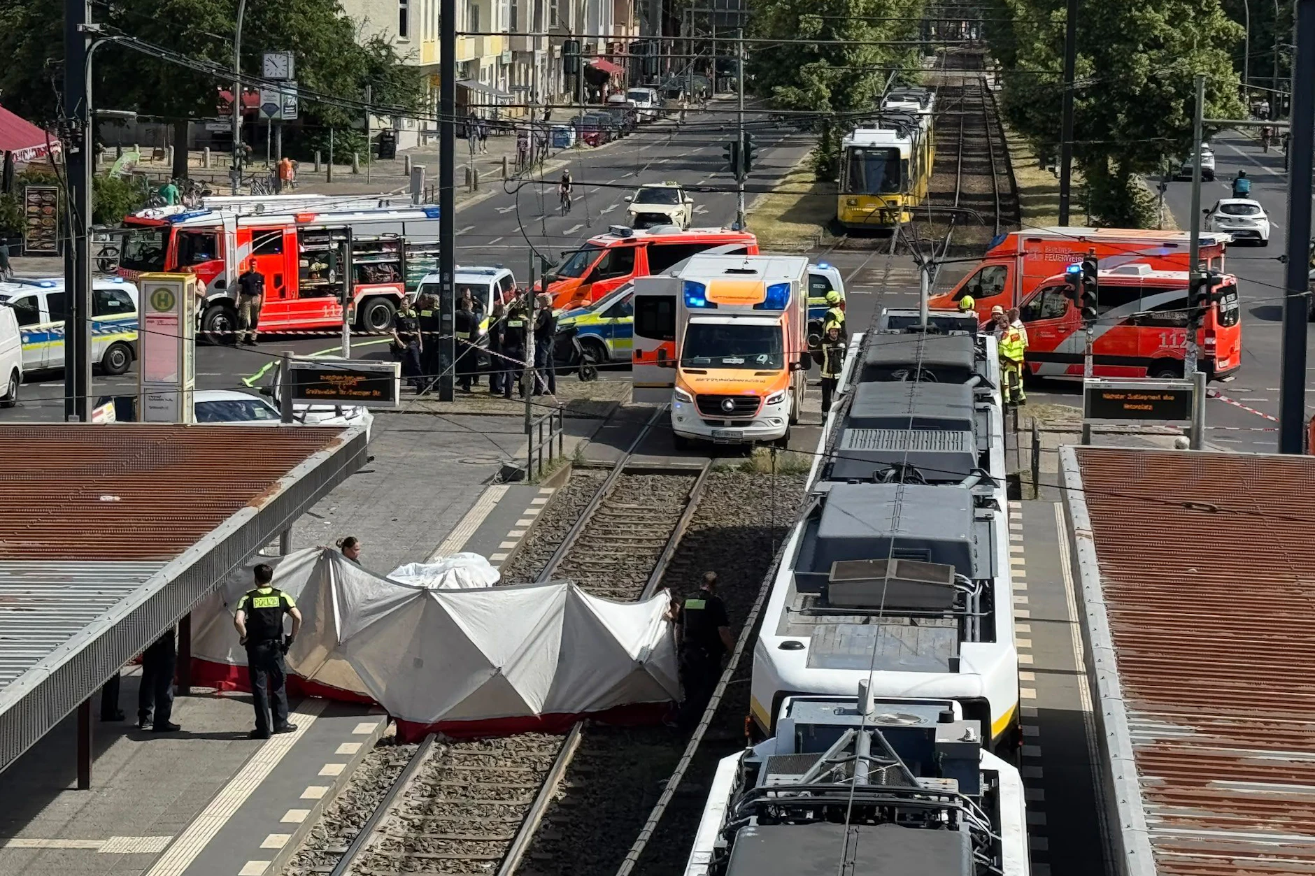 Polizisten bauen einen Sichtschutz auf. An der Kreuzung Grellstraße/Greifswalder Straße schleuderte ein PKW  in eine Tramhaltestelle und verletzte einen Mann tödlich.