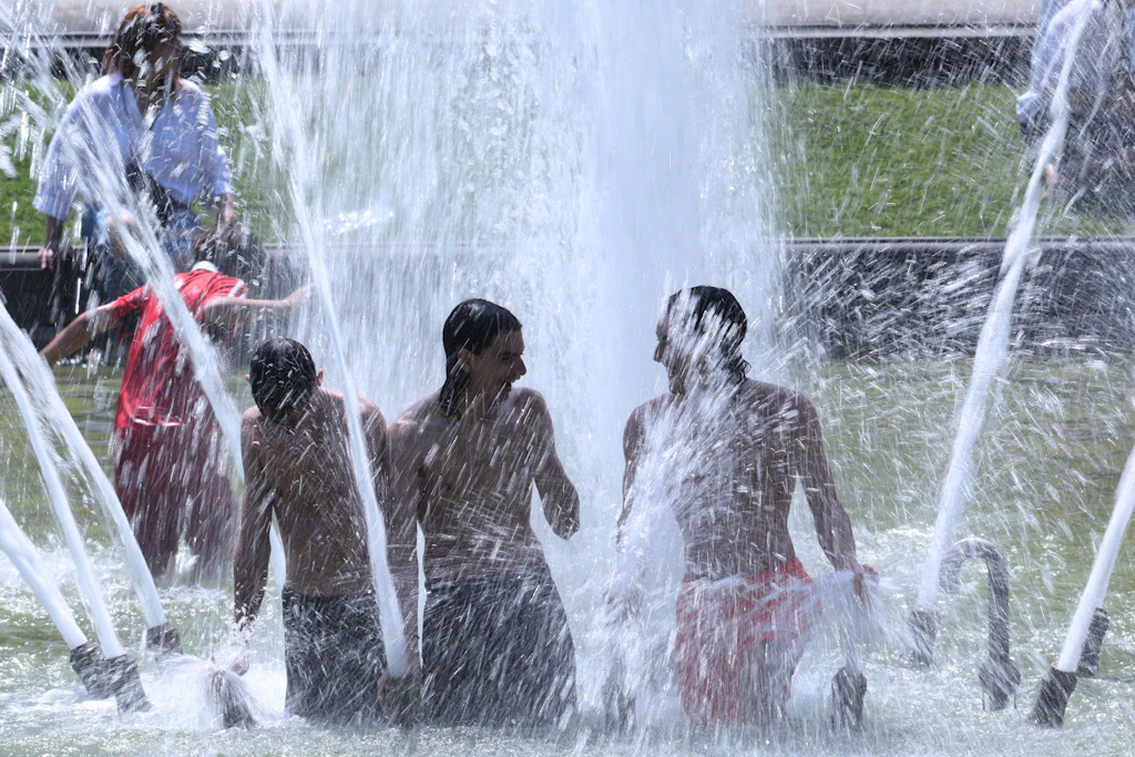 Im Cinquantenaire-Park in Brüssel erfrischen sich Menschen in einem Springbrunnen.