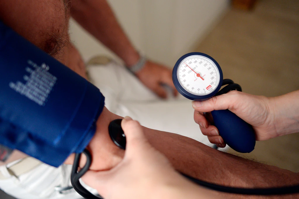 Eine Hausärztin misst den Blutdruck eines Patienten: Die TK stellt den Nutzen von Hausarztverträgen infrage.