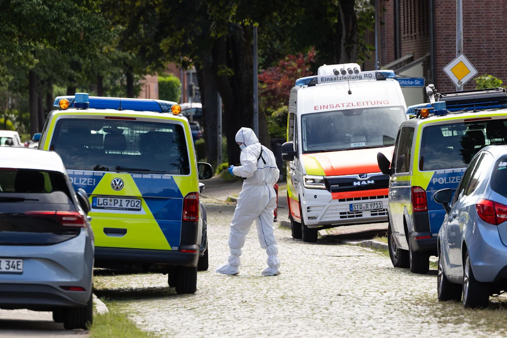 Einsatzkräfte der Spurensicherung stehen nach den Morden in Tatortnähe.