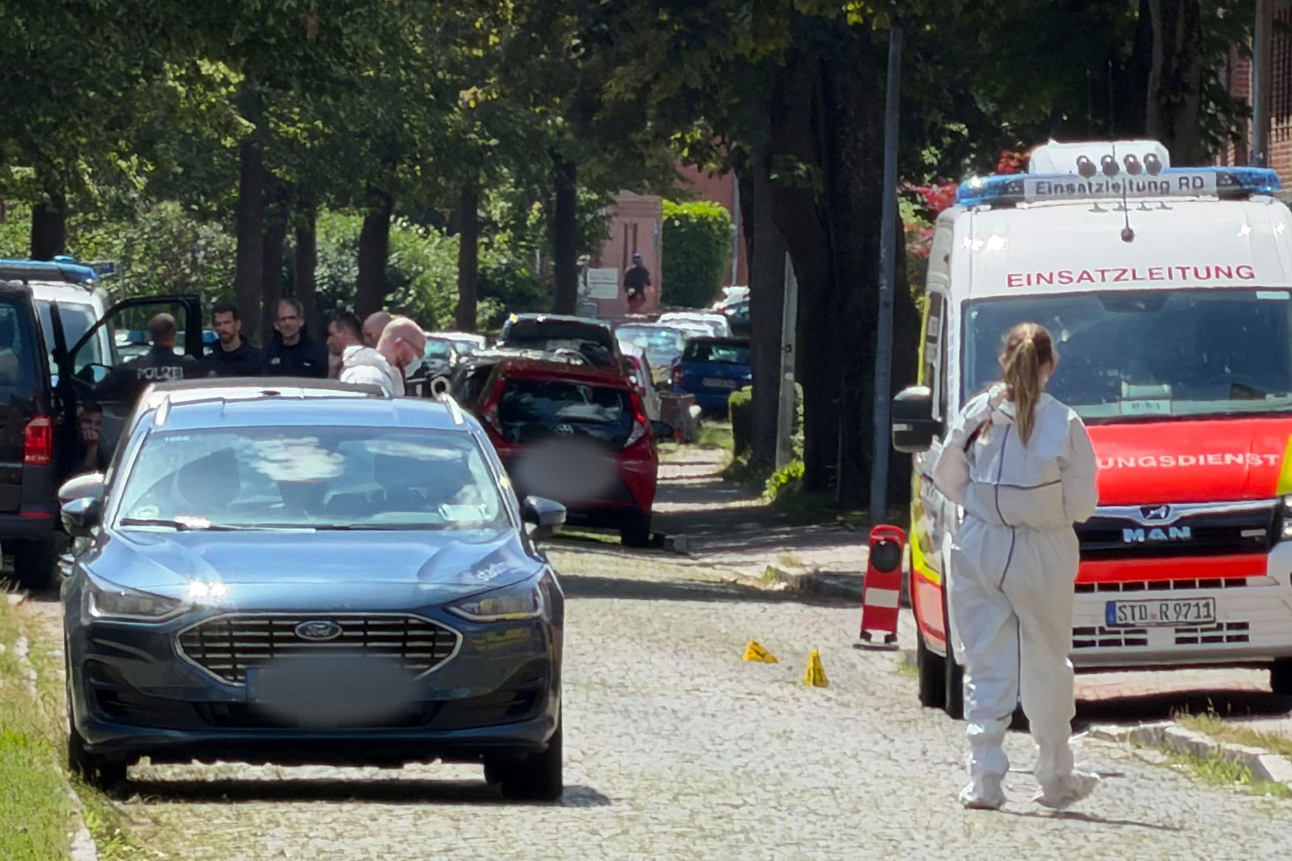 Einsatzkräfte und Spurensicherung stehen auf einer Straße in Stade.