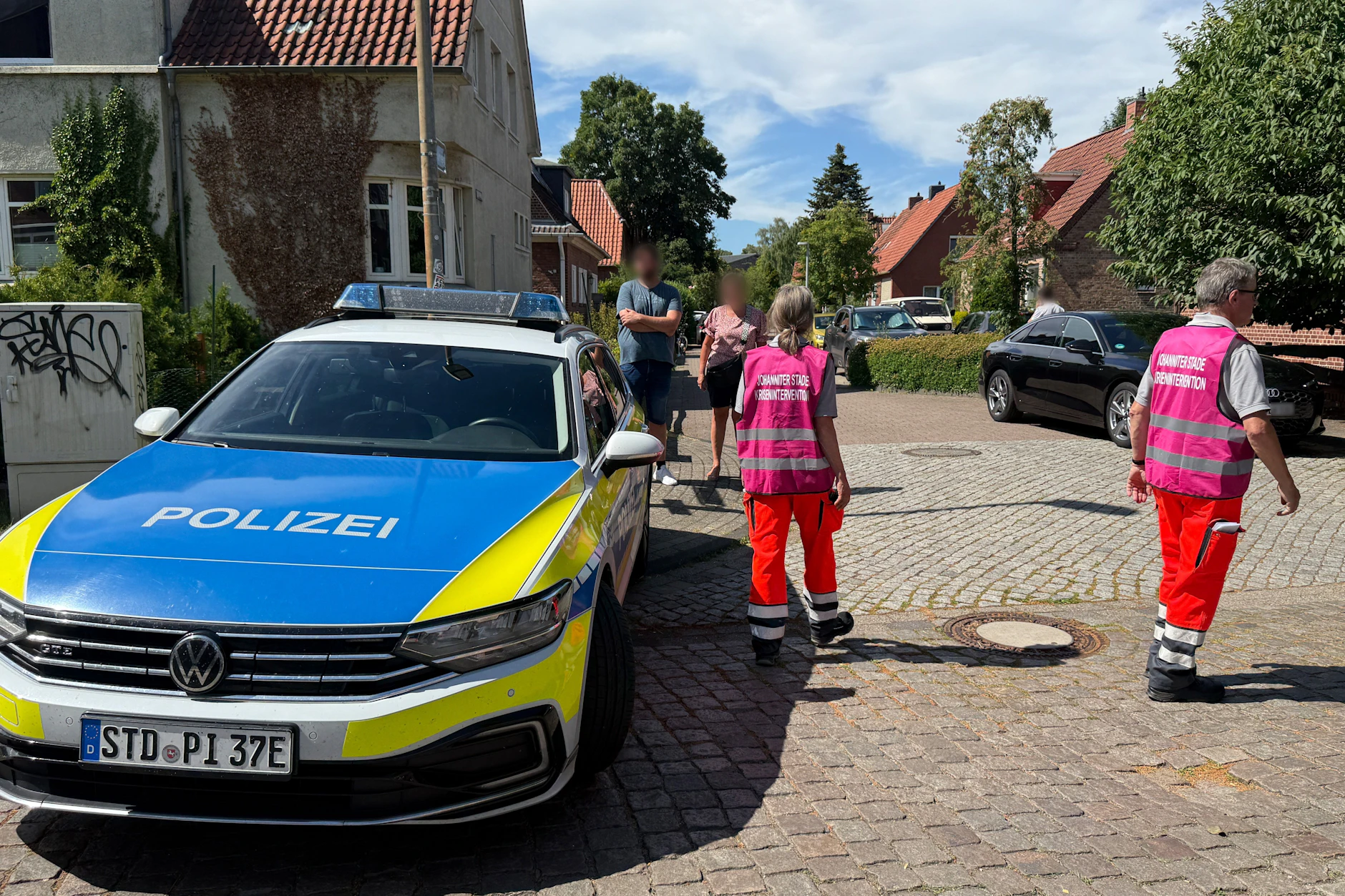 Einsatzkräfte zur Krisenintervention stehen auf einer Straße in Stade. Zwei Tatverdächtige wurden festgenommen.