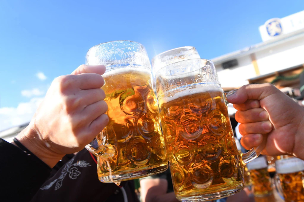 Besucher stoßen auf dem Oktoberfest mit Maßkrügen voller Bier an – auch weil das Wasser dieses Jahr zu teuer ist?
