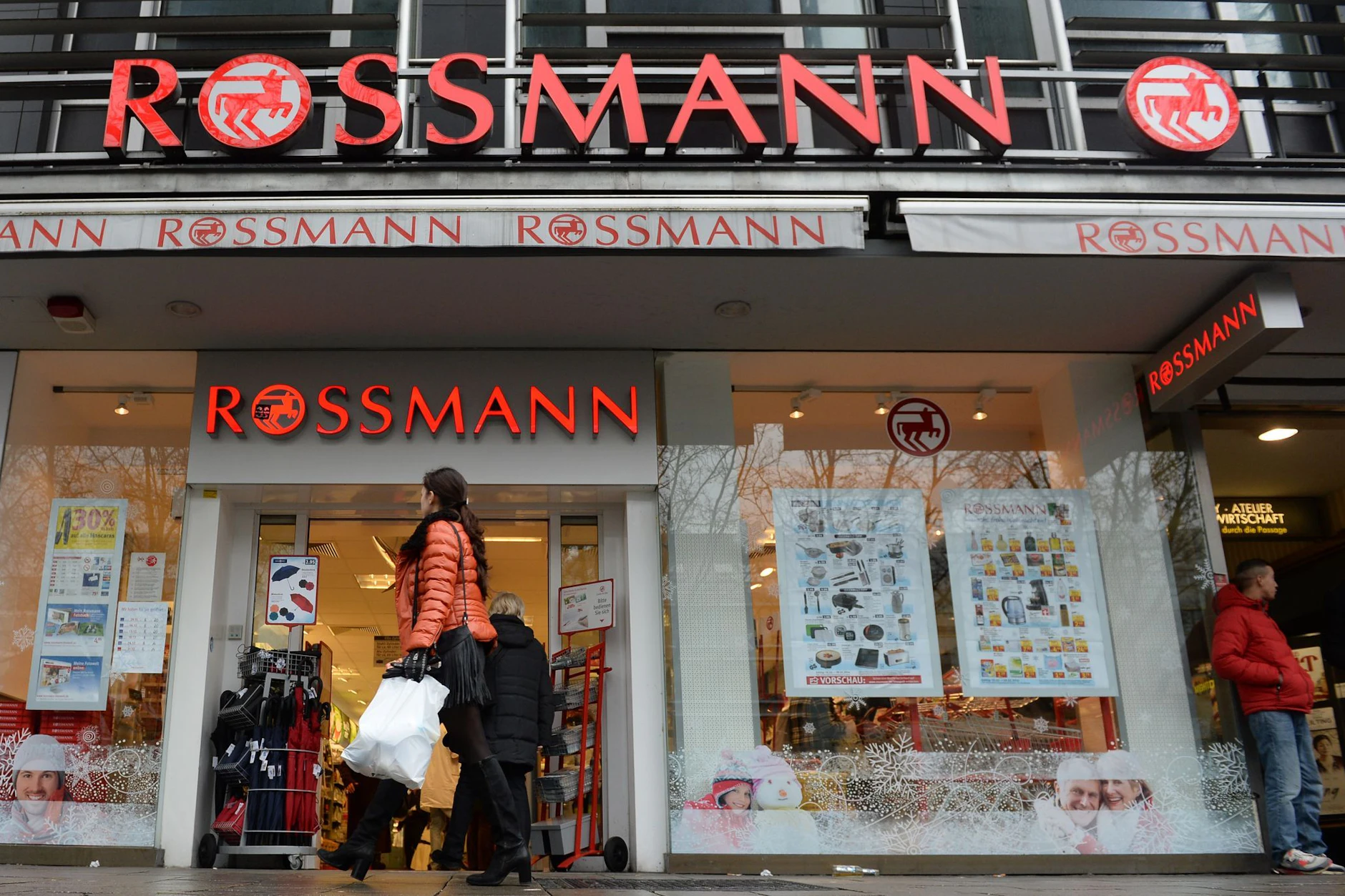 Eine Frau geht an einer Rossmann-Filiale vorbei.