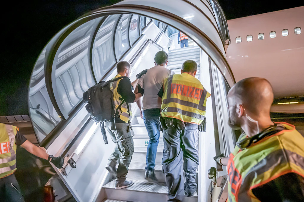 Polizeibeamte begleiten einen Afghanen auf dem Flughafen Leipzig-Halle in ein Charterflugzeug.