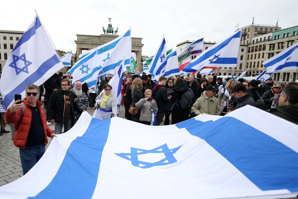 Teilnehmer einer proisraelischen Demonstrationen halten gemeinsam eine große israelische Flagge.