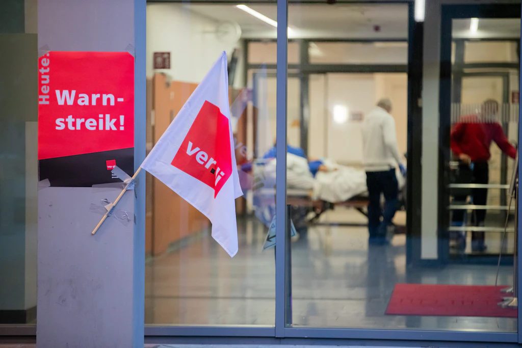 Eine Verdi-Fahne sowie ein Plakat hängen bei einem Streik von Beschäftigten der Berliner Charité.