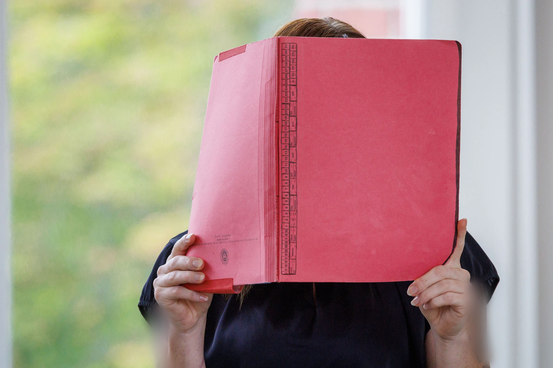 Gina H. versteckt sich vor Gericht hinter einem roten Hefter vor den Pressefotografen .Ihr wird vorgeworfen, den kleinen Fabian aus Güstrow getötet zu haben.