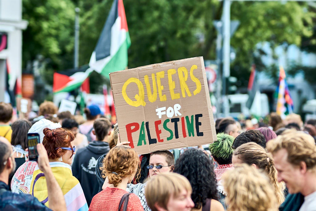 Teilnehmer der Internationalist Queer Pride for Liberation (IQP) halten bei einer Aktion am Südstern in Kreuzberg eine Pappe mit der Aufschrift „Queers for Palestine“ hoch.