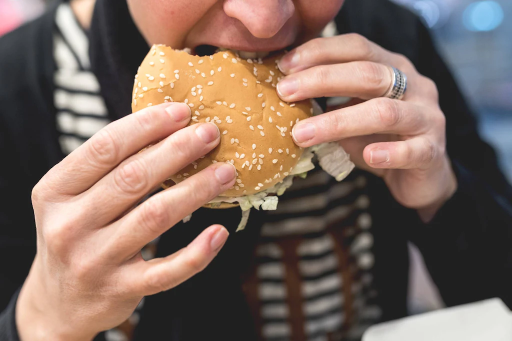 Eine junge Frau beißt in einen Hamburger.
