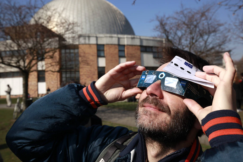 Interessierte beobachten die Sonnenfinsternis am Planetarium Prenzlauer Allee.