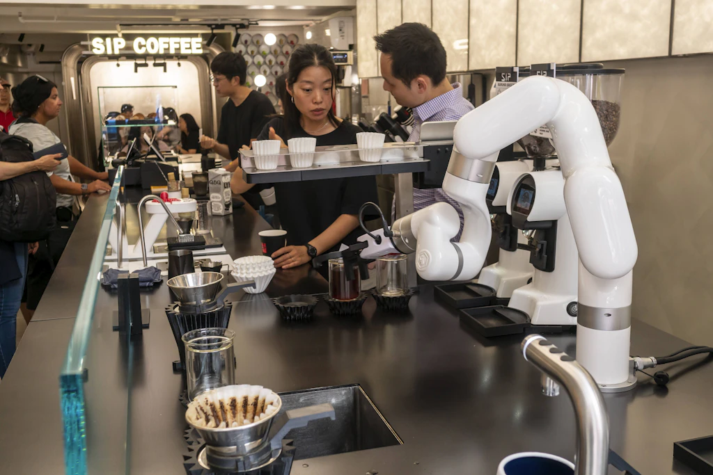 Roboterarme bereiten in einem Café Kaffee für Kunden zu.