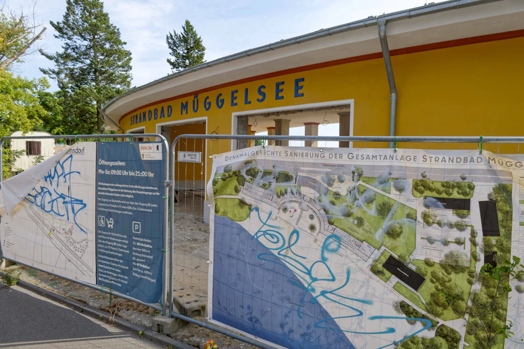 Hinter Bauzaun und besprühten Info-Tafeln: Das Eingangsgebäude des Strandbads Müggelsee – fertig wird das Bad später als geplant.