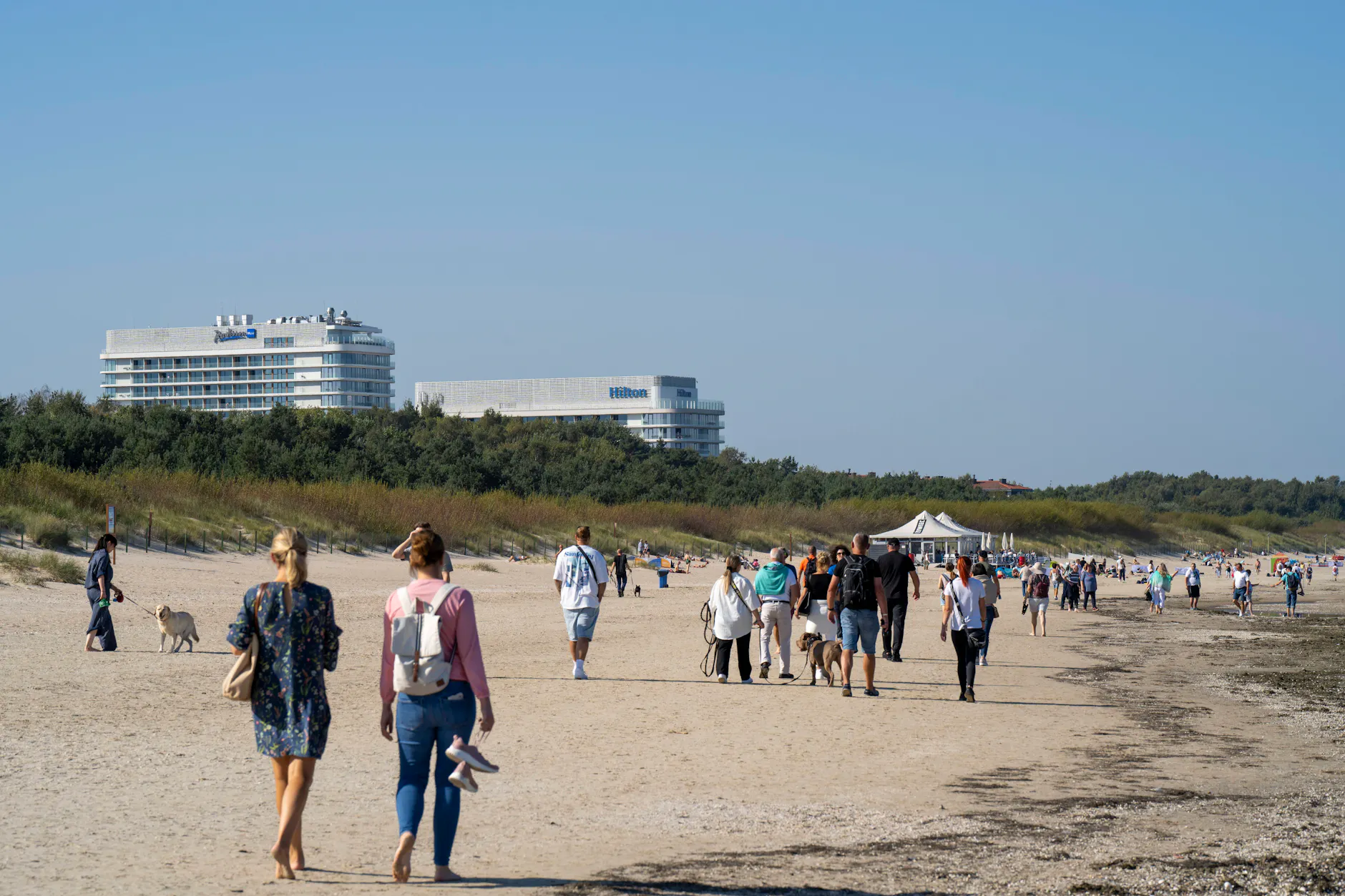 Touristen laufen am Sandstrand von Swinemünde entlang. Die Grenzstadt hat einen rund zehn Kilometer langen Strand.