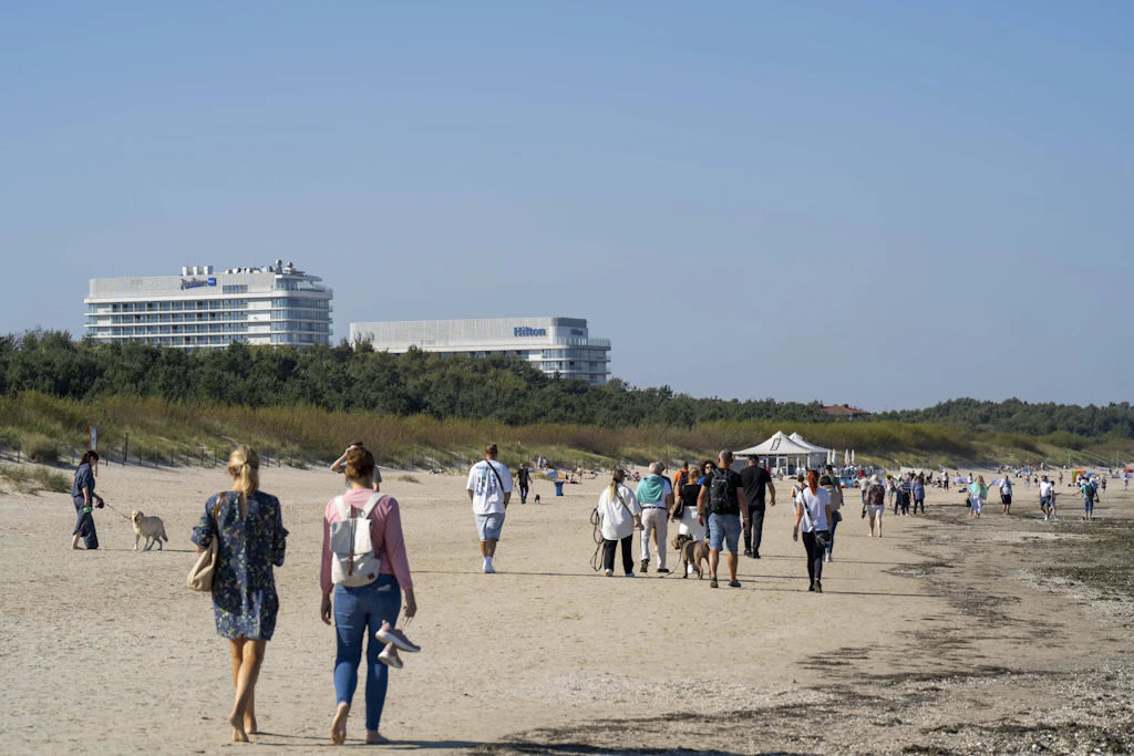 Touristen laufen am Sandstrand von Swinemünde entlang. Die Grenzstadt hat einen rund zehn Kilometer langen Strand.