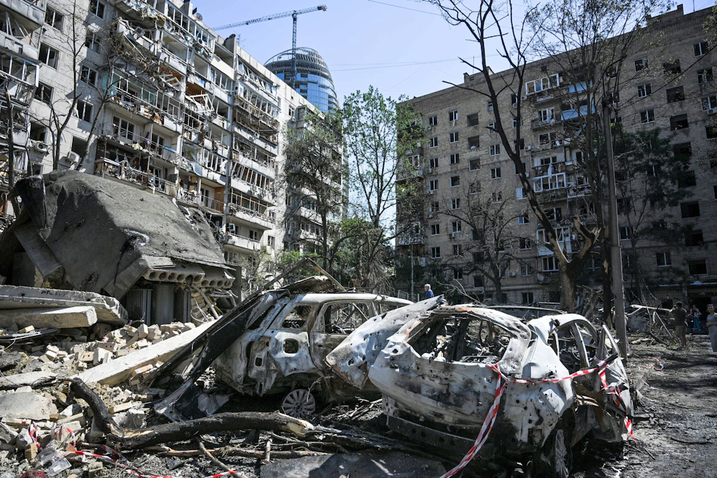 Vor einem Wohnhaus im Kiewer Stadtteil Pecherskyi, das durch einen russischen Raketen- und Drohnenangriff beschädigt wurde, stehen ausgebrannte Autos.