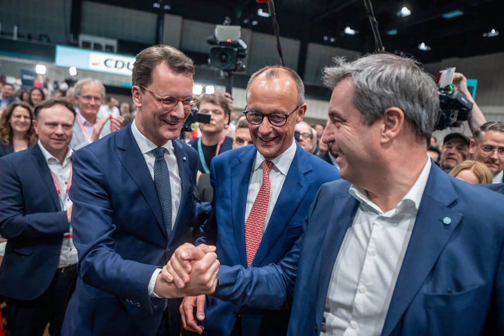 Bundeskanzler Friedrich Merz (M.) steht zwischen Hendrik Wüst (l.) und Markus Söder (r.).