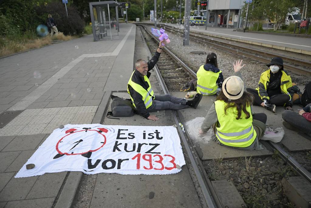 Demonstrierende haben sich auf den Straßenbahnenschienen am Gothaer Platz festgeklebt und blockieren sie.