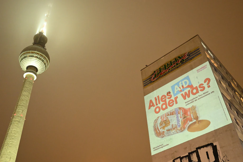2026: Eine Projektion mit dem Slogan "Alles AfD, oder was" leuchtet an einer Hauswand am Alexanderplatz neben dem Fernsehturm. Die Großprojektion ist Teil einer bundesweiten Kampagne gegen den Unternehmer Müller.