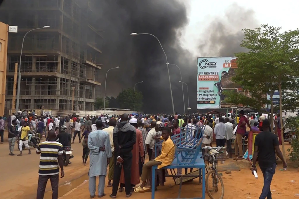 Vor dem brennenden Hauptquartier der Regierungspartei demonstrieren Anhänger meuternder Soldaten in Niamey. Die politische Lage in dem Land ist instabil.