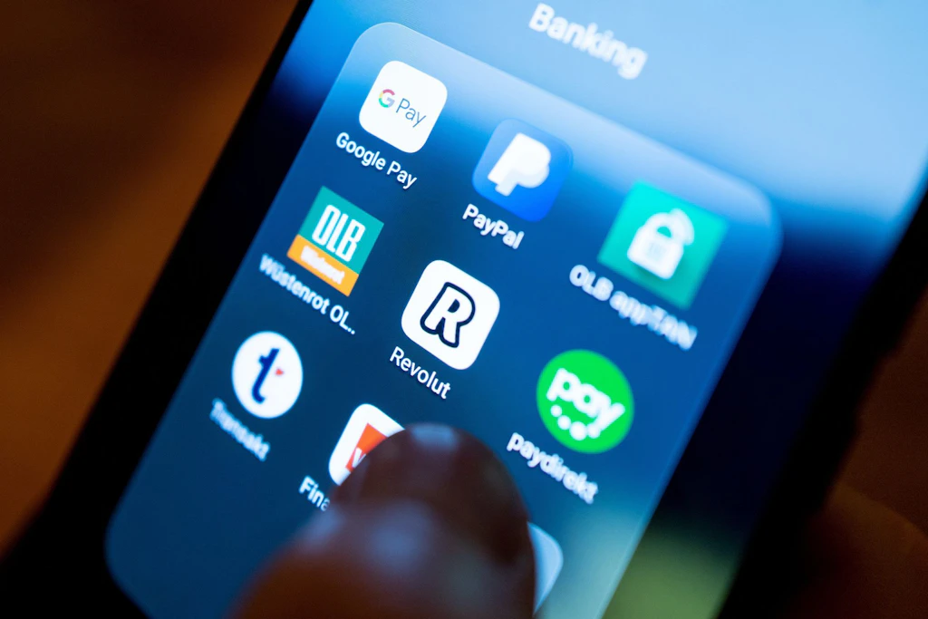 Die App der britischen Finanzplattform Revolut auf dem Bildschirm eines Smartphones neben Apps weiterer Finanz- und Bezahldienste.