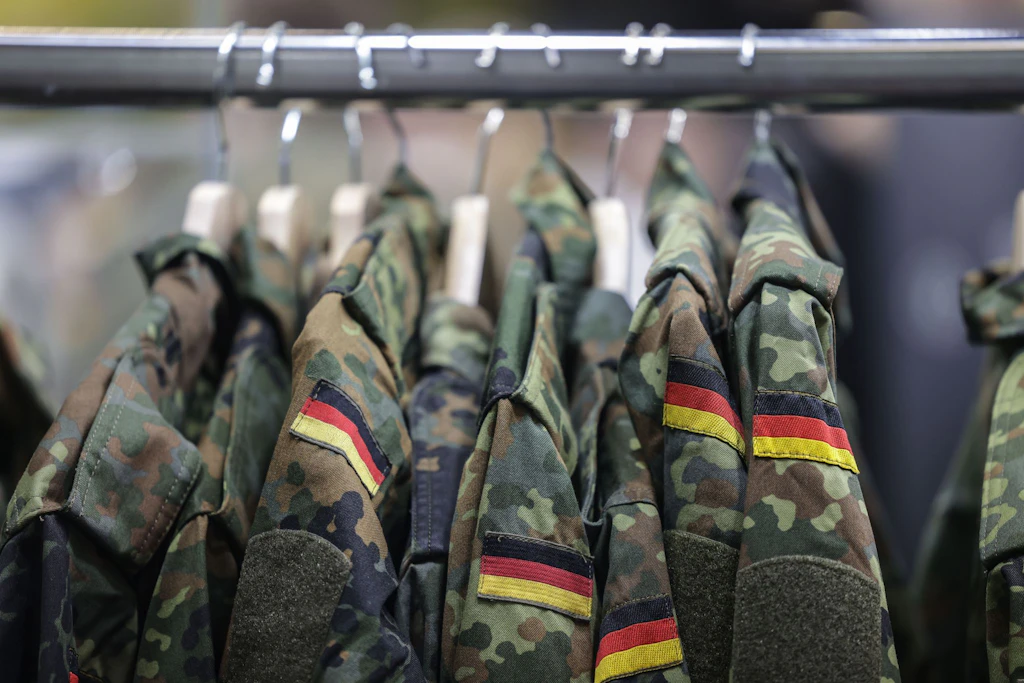 Feldjacken hängen für neue Freiwillige bei einem Messestand der Bundeswehr bereit.