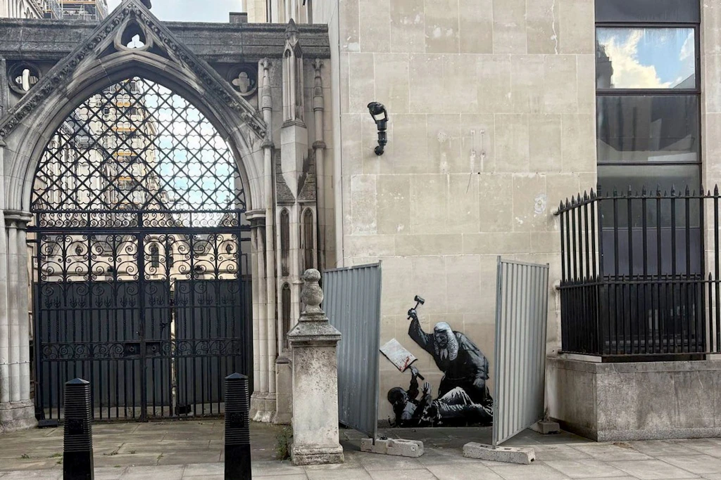 Kunstwerk des Straßenkünstlers Banksy an der Fassade des Royal Courts of Justice