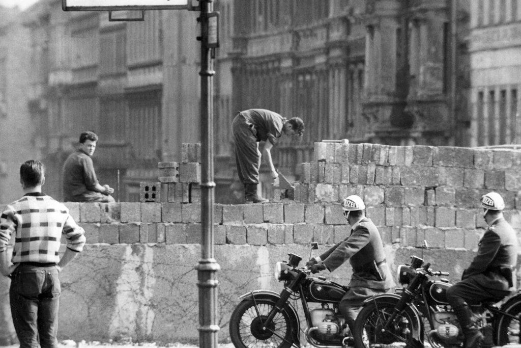 Der Mauerbau vor 65 Jahren. West-Berliner Polizisten auf ihren Motorrädern schauen im August 1961 überrascht auf die Mauer, die dort plötzlich an der Bernauer Straße entsteht.
