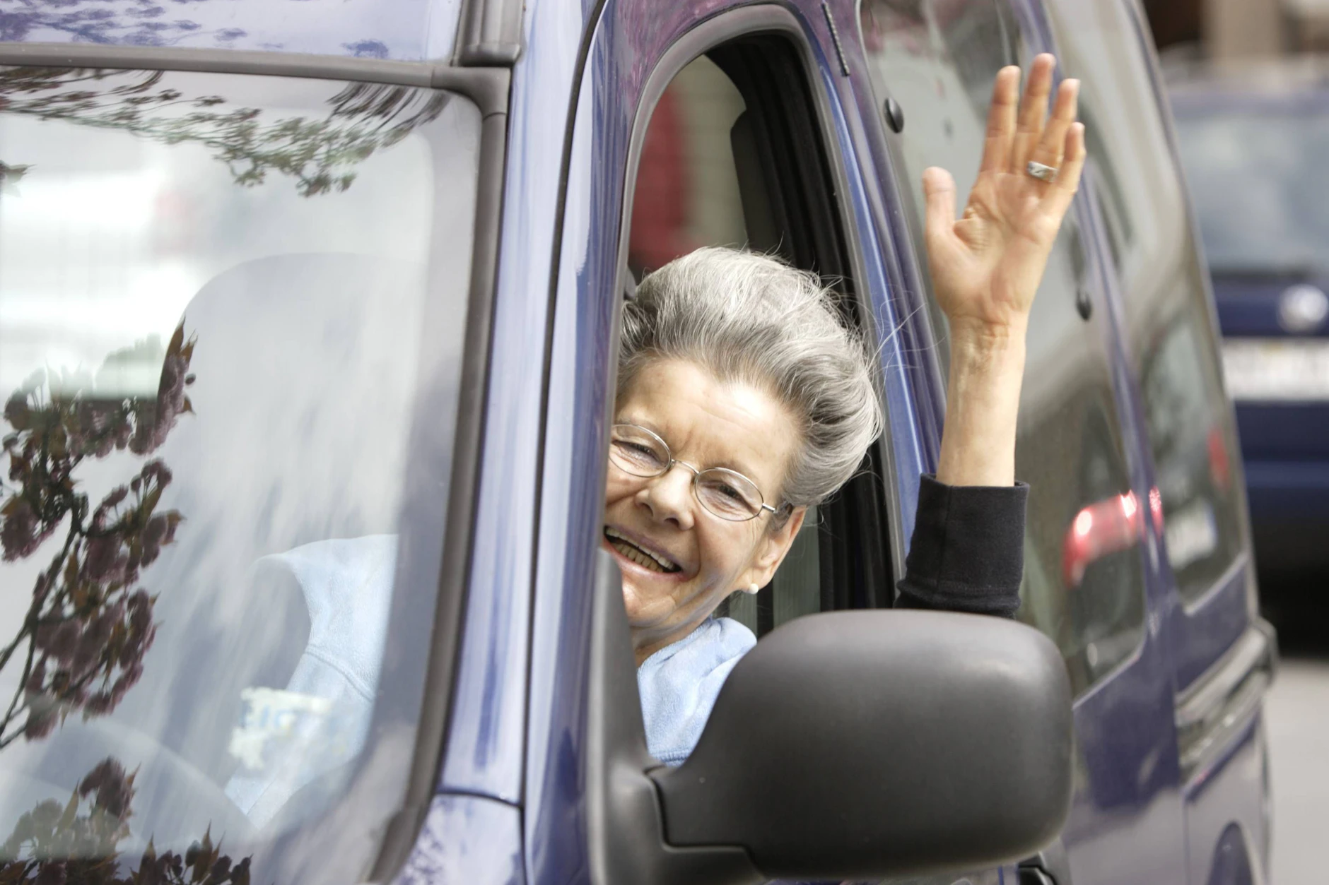 Eine Seniorin grüßt in Deutschland aus ihrem Auto. Für Senioren bedeutet der Führerschein unter anderem Freiheit und Selbstbestimmung.