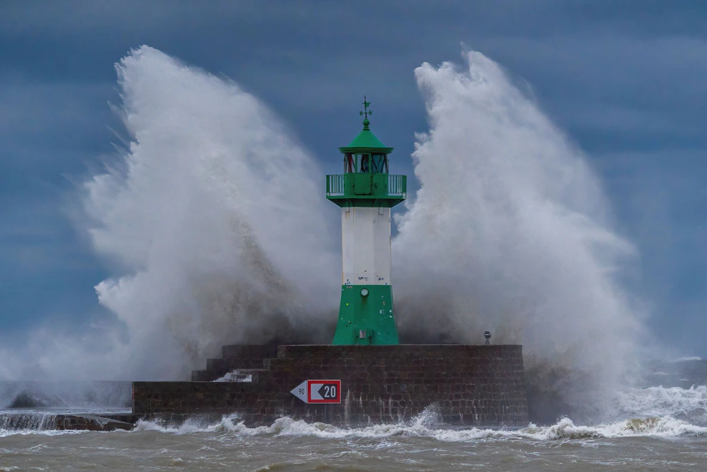 Wellen brechen an einem Leuchtturm in Sassnitz.