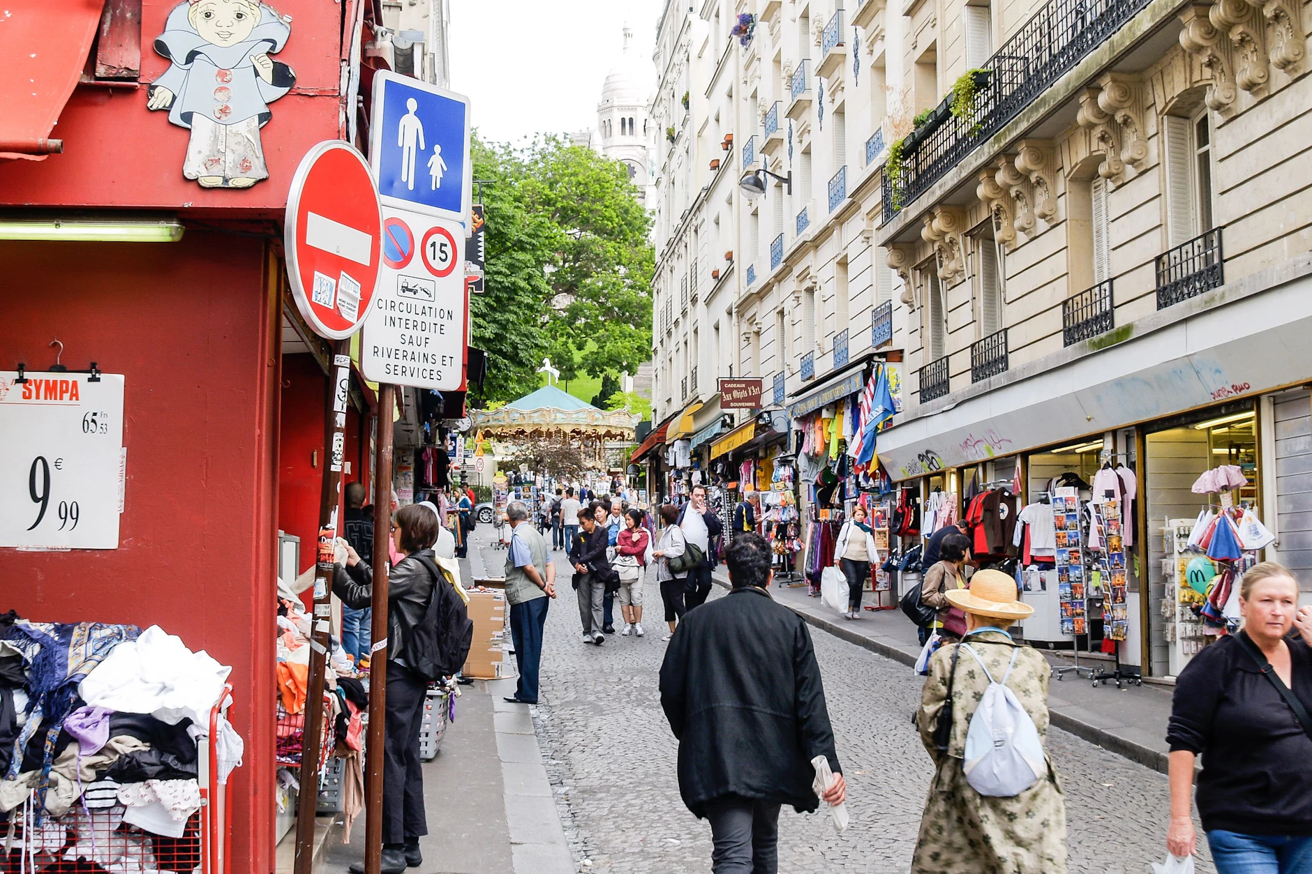 Souvenirshops und Touristenströme im Pariser Viertel Montmartre, im Hintergrund die Sacré-Cœur. Rund elf Millionen Besucher zieht die Basilika jährlich an.
