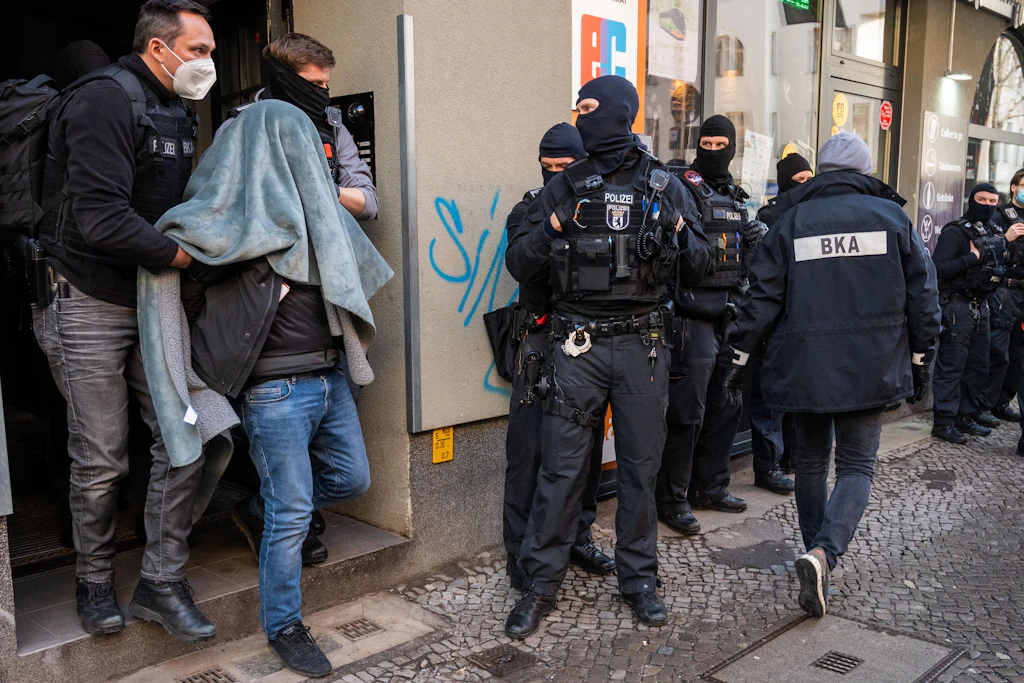 Großrazzia gegen Clankriminalität in Berlin: Ein Mann wird mit einer Decke über dem Kopf von der Polizei abgeführt.
