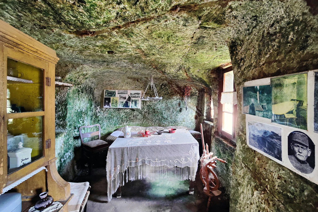Wohnstube im Fels: Historische Möbel, Spinnrad und Spitzendecke vor rohem Sandstein – so richtete der Verein eine der Höhlenwohnungen in Langenstein wieder ein.