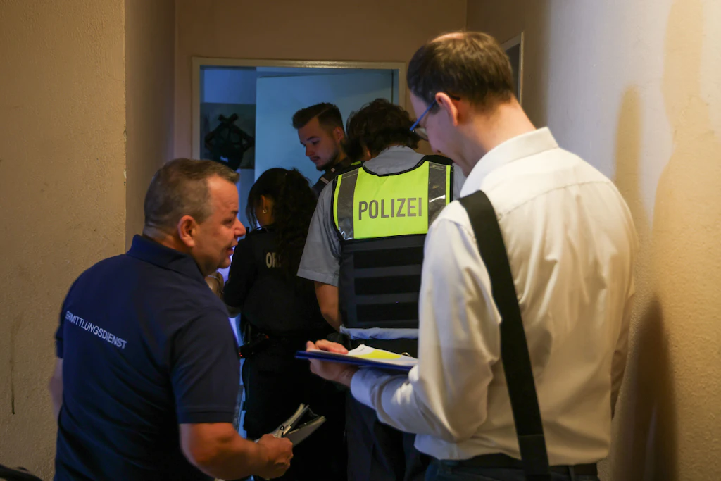 Mitarbeiter verschiedener Behörden kontrollieren die Bewohner in einer Wohnung.