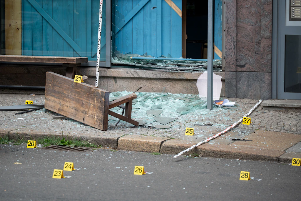 Zerborstene Scheiben und Trümmer vor dem betroffenen Lokal in Leipzig. Die gelben Nummern markieren Spuren, die von der Polizei nach der Explosion gesichert wurden.