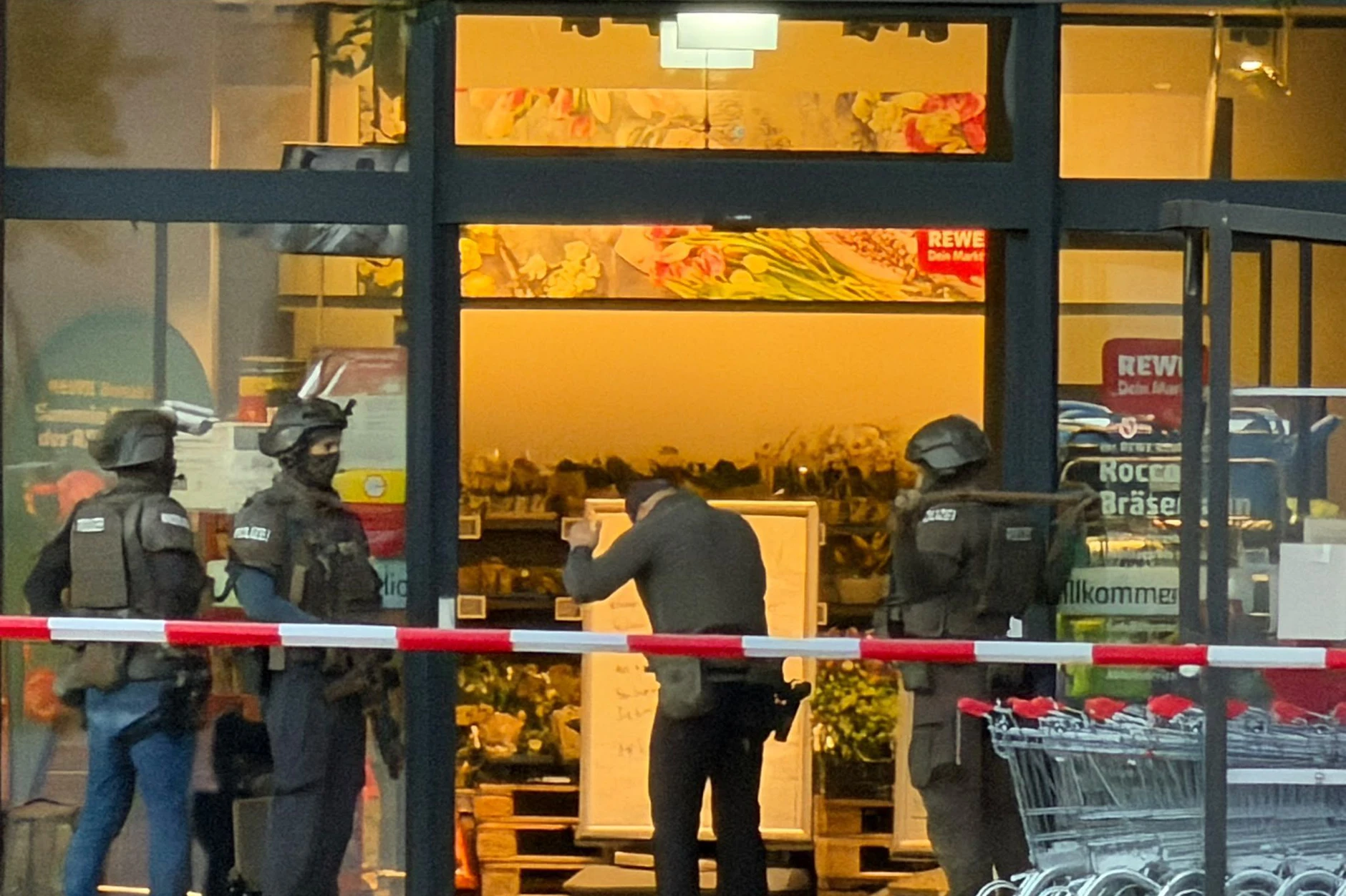 Ein bewaffneter Vermittler, geschützt von SEK-Beamten, spricht durch die Tür mit dem Geiselnehmer.