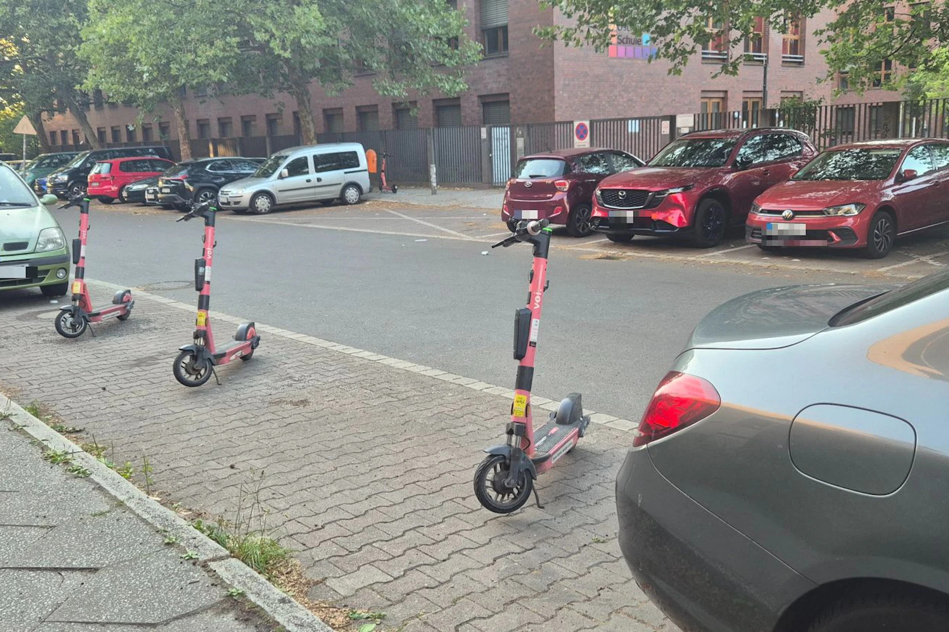 Drei E-Scooter blockieren eine Parklücke in einer hart umkämpften Straße. Dahinter steckt eine dreiste Masche.
