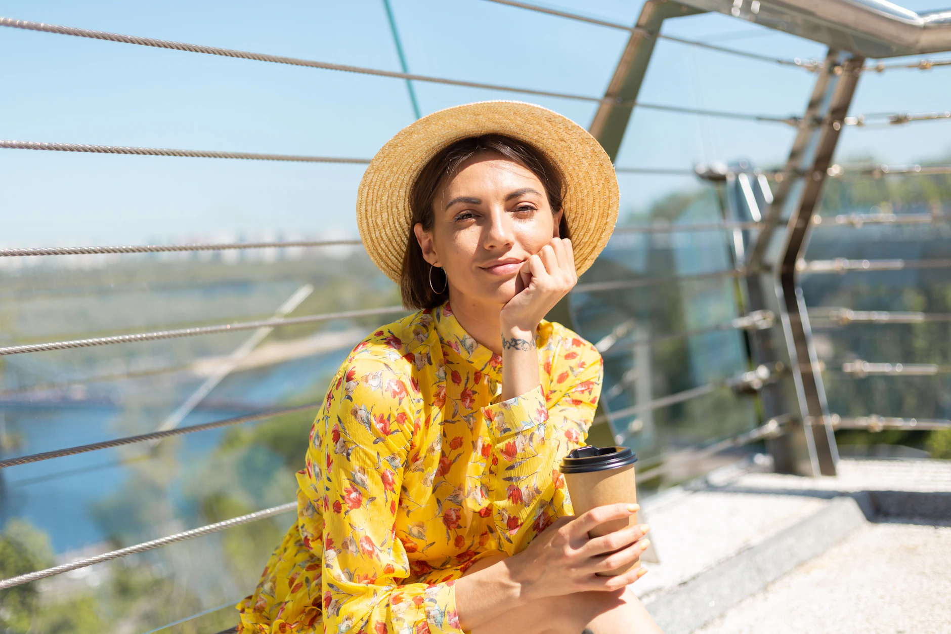 Im Sommerkleid und mit Kaffee in der Hand genießt diese Frau einen ruhigen Moment in der Sonne. Genau diese leichte Stimmung passt perfekt zum Samstag.