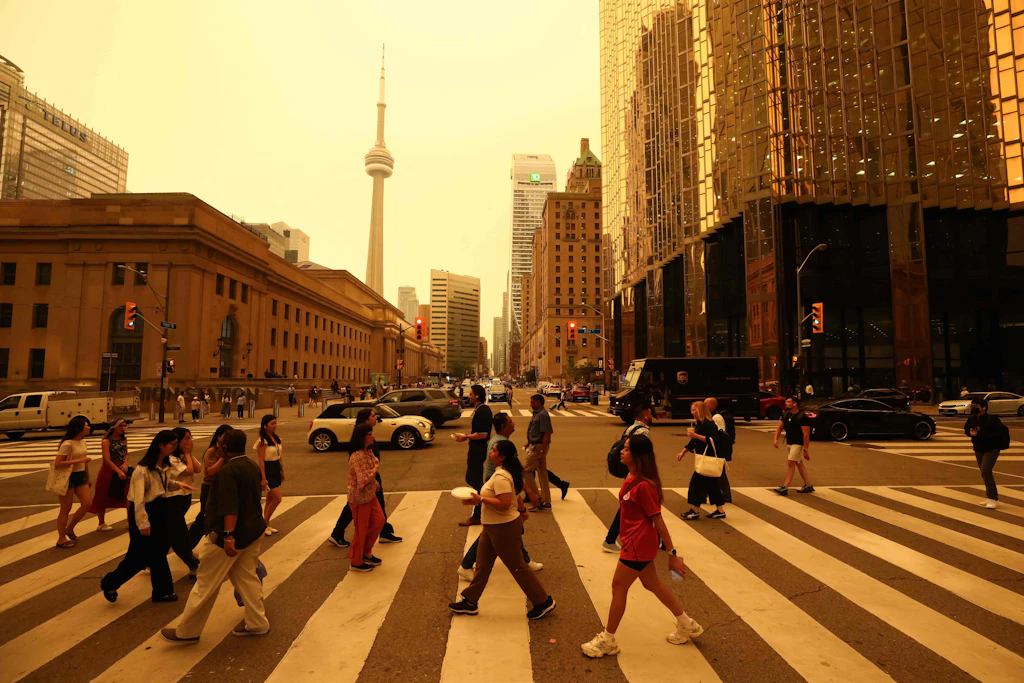 Menschen überqueren im rauchverhangenen Toronto eine Straßenkreuzung.
