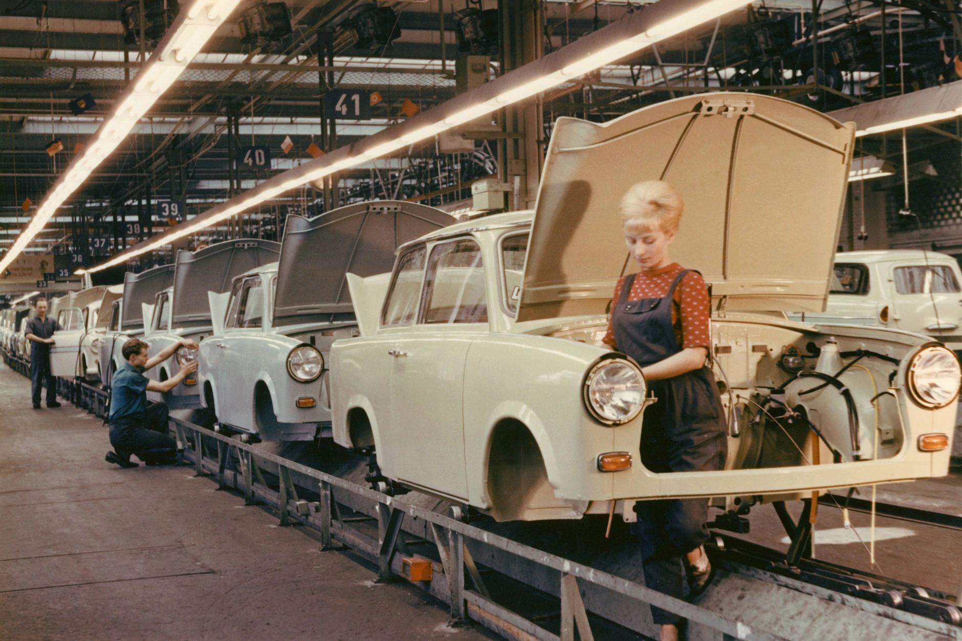 Eine Mitarbeiterin schraubt in der Werkshalle des VEB Sachsenring an einem Trabant.