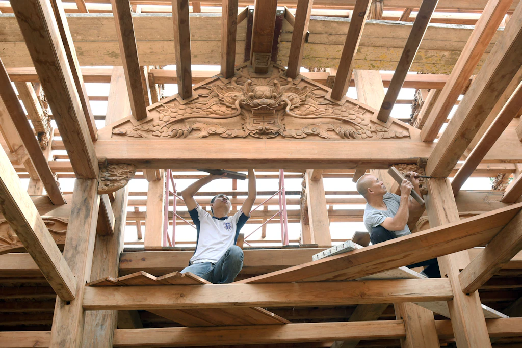 Die vietnamesischen Tempelbauer Nguyen Quy Giap (re.) und Nguyen Danh Cuong bauen den Tempel aus rotem Lärchenholz auf.