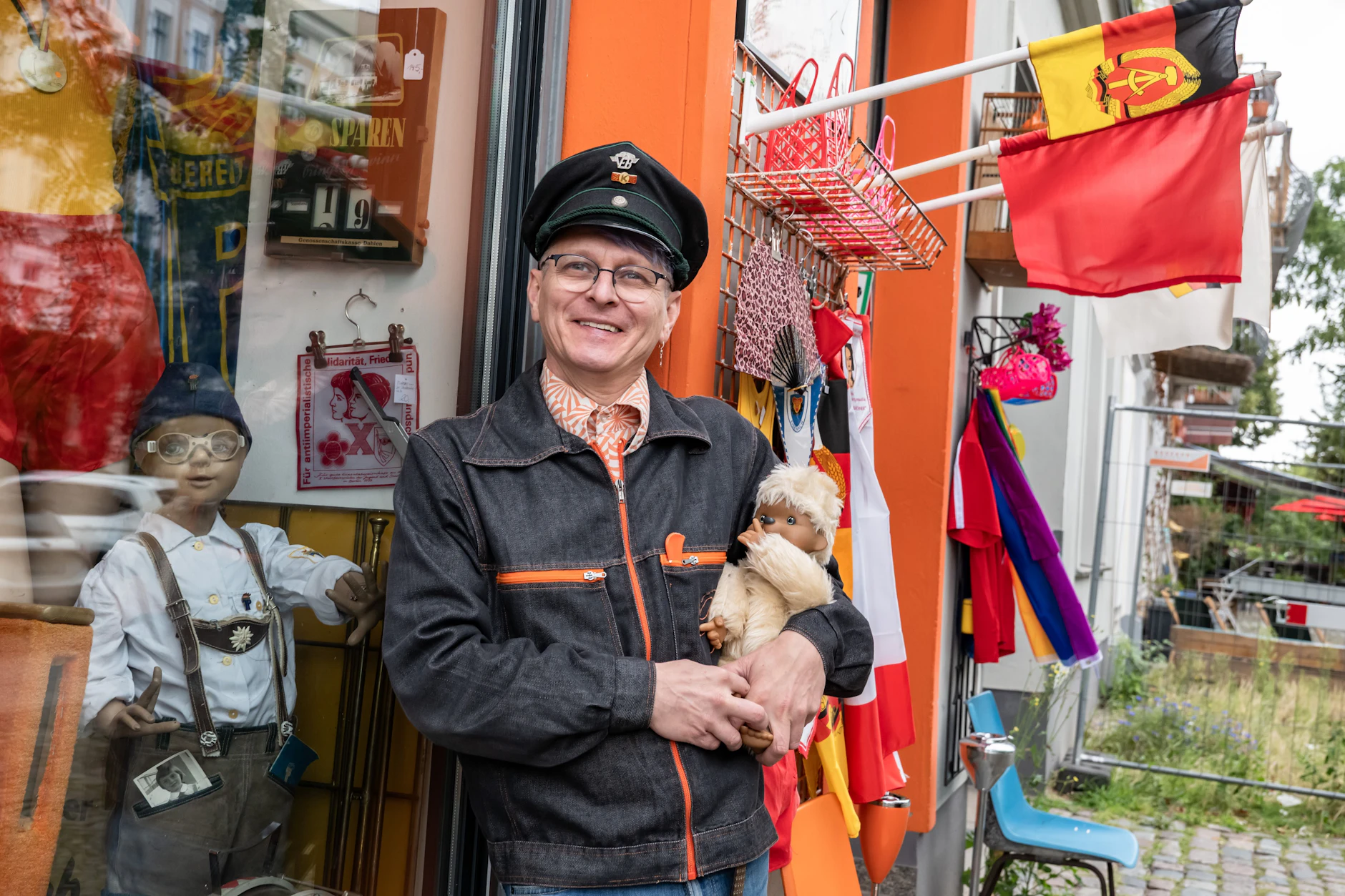 Mario Schubert mit einem DDR-Monchichi vor seinem Laden VEB Orange in Berlin.