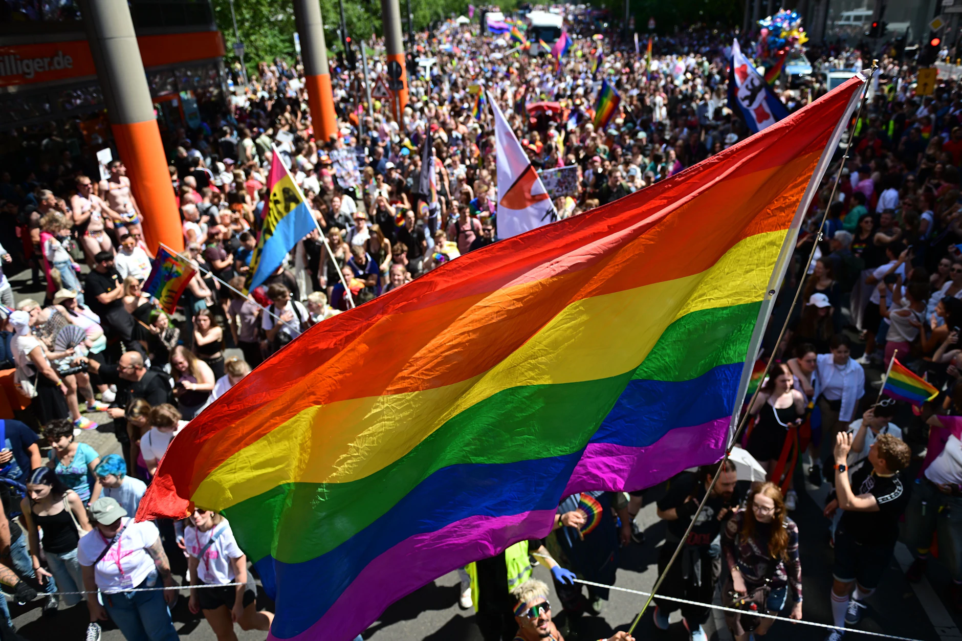 Menschen demonstrieren mit einer Regenbogenflaggge unter dem Motto „Haltung ist hot“ beim Christopher Street Day.