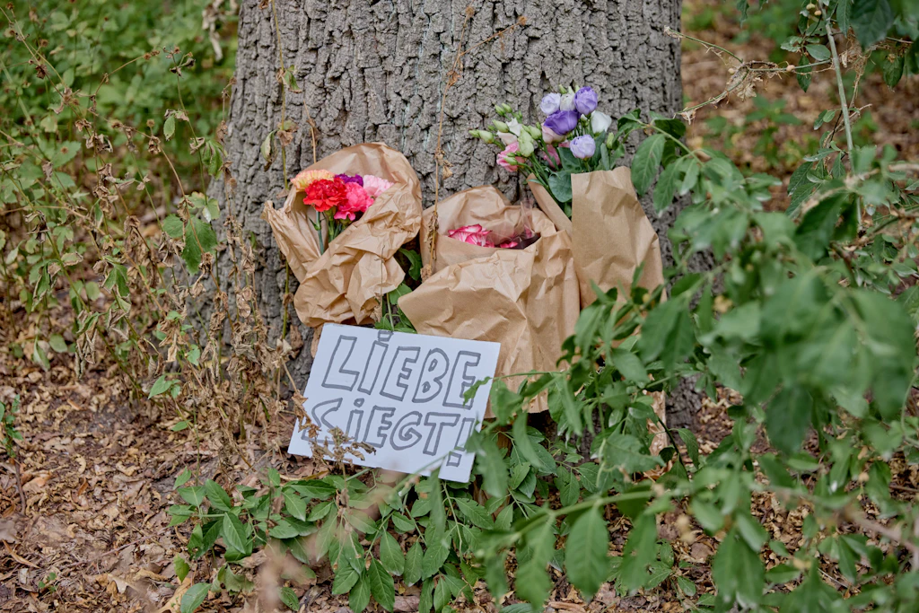 Blumen liegen an einem Baum nahe dem Tatort. Immer mehr Menschen kommen in den Tiergarten, um zu trauern.