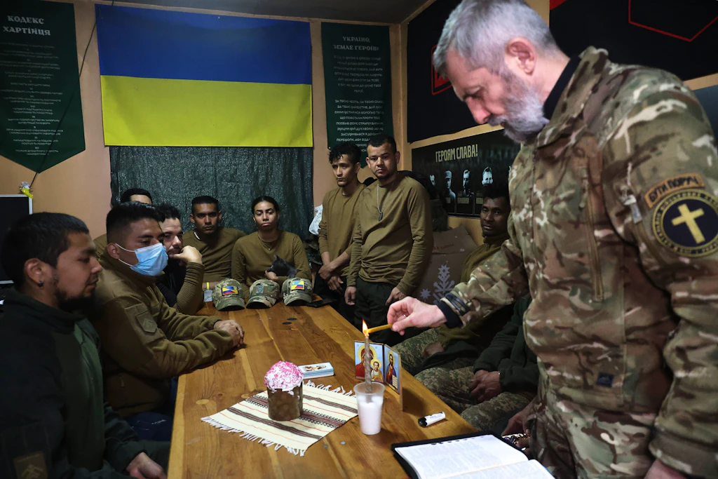 Ein Militärseelsorger zündet während eines Gottesdienstes mit ausländischen Soldaten des Chartija-Korps eine Kerze an. 