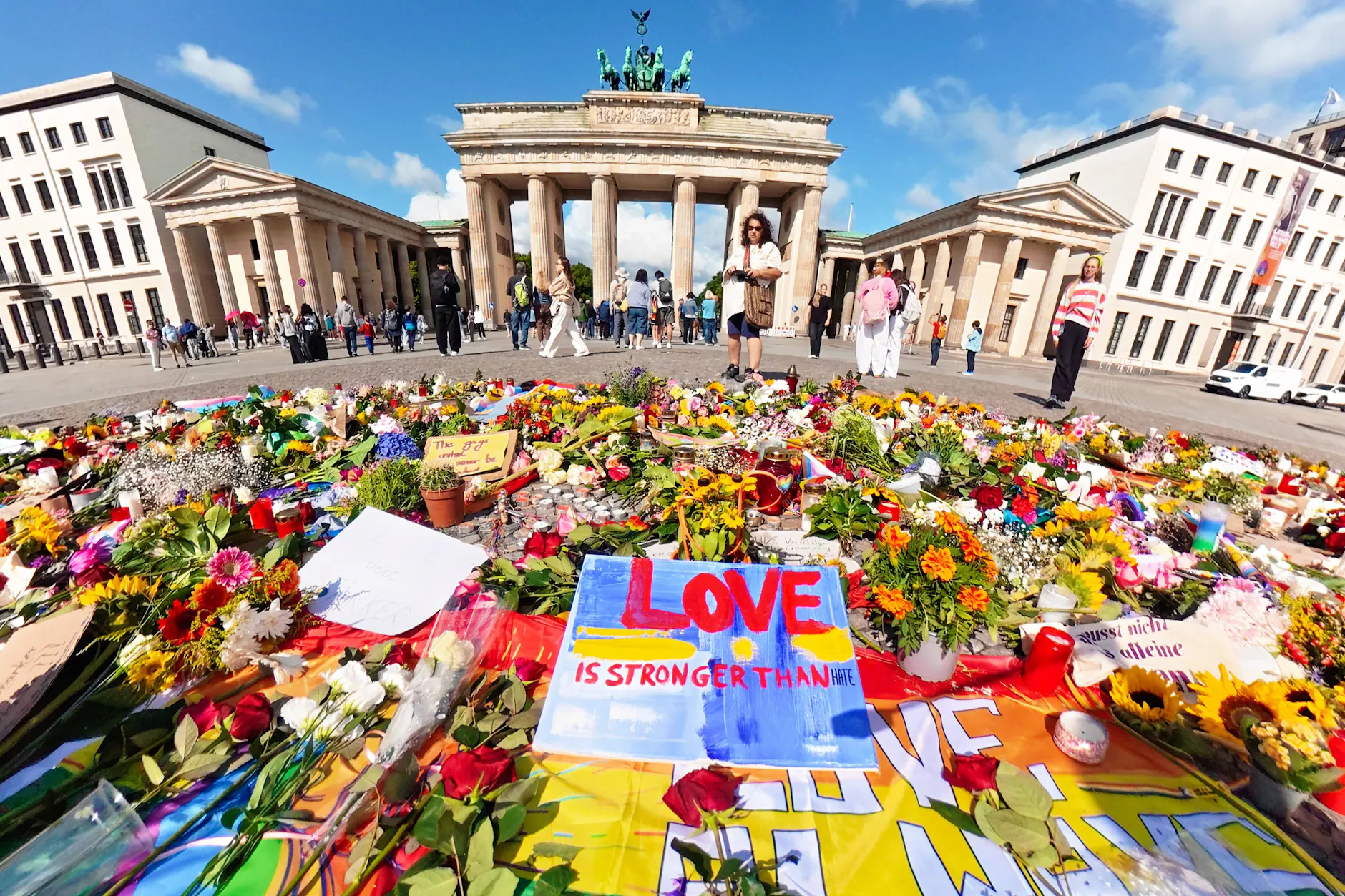 Tausende Menschen haben vor dem Brandenburger Tor Blumen, Kerzen und Regenbogenfahnen niedergelegt und trauern um die Opfer des CSD-Anschlags.