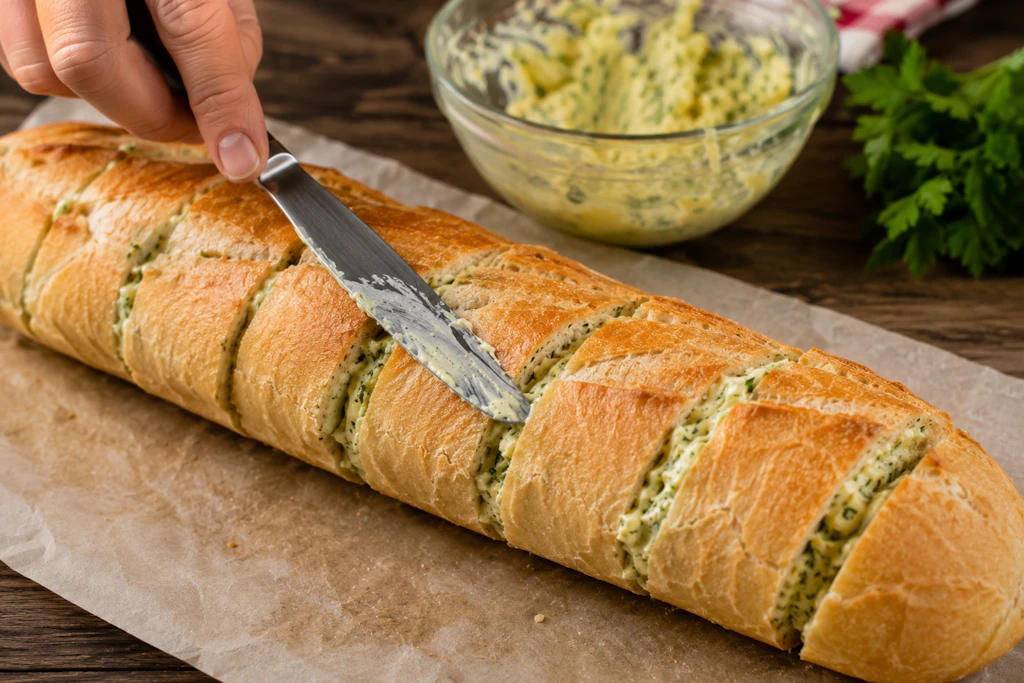 Beim Kräuterbaguette wird die schnell zubereitete Kräuterbutter einfach in die Zwischenräume des Baguettes gestrichen.