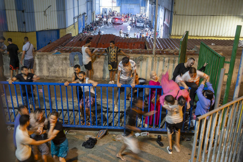 Menschen überwinden nach ihrer Ankunft in Ceuta eine Absperrung. Unter den Tausenden Neuankömmlingen sind auch Frauen und Kinder.