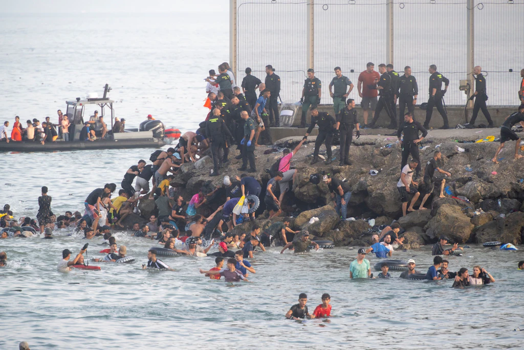 Dutzende Migranten kommen nach dem Überqueren der Grenze in Ceuta an. Auch als am Donnerstag, dem 30. Juli, die Nacht hereinbrach, strömten weiterhin zahlreiche Menschen unkontrolliert aus Marokko nach Ceuta. Seit den frühen Morgenstunden hatten Tausende von Migranten die autonome Stadt erreicht, indem sie schwimmend oder zu Fuß die Mole umgingen, die die autonome Stadt von Marokko trennt.