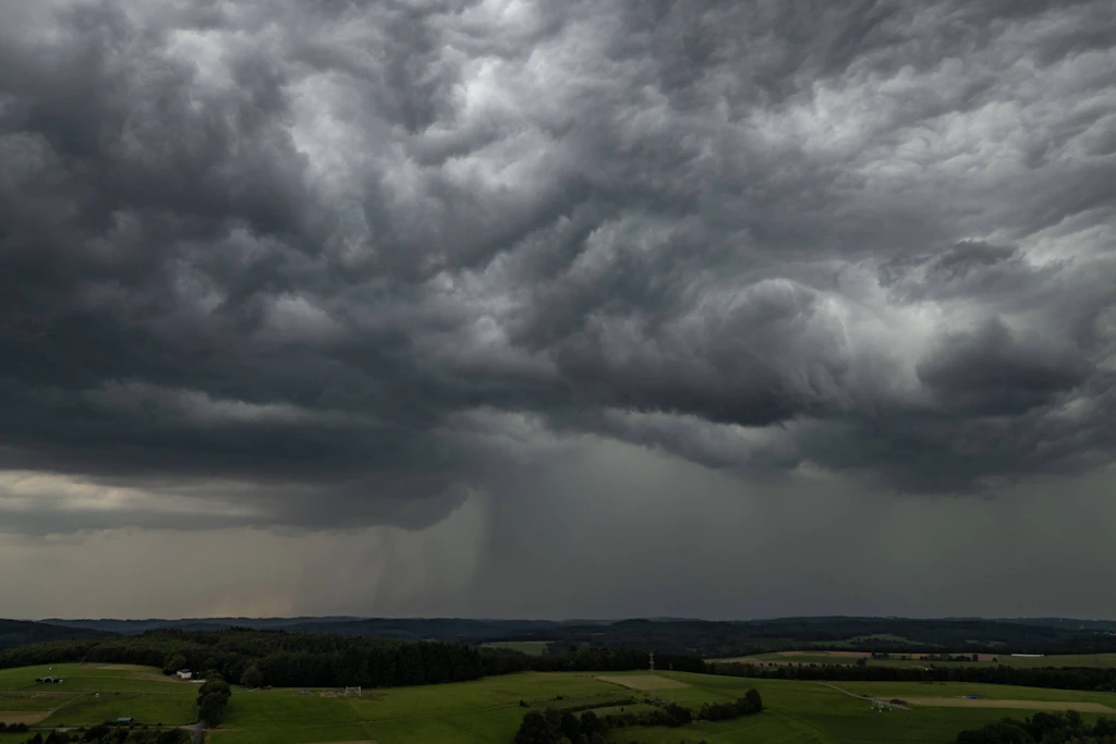 Dunkle Wolkenwand über einer Feldlandschaft (Symbolbild): Fast ganz Ostdeutschland liegt am Freitag südlich der Unwetterlinie, die der DWD von der Mosel bis zum Oderbruch zieht.